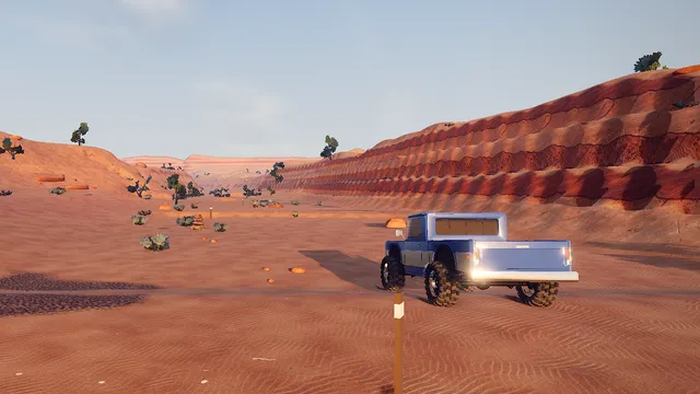 A trail truck in a sandy wash beside stepped red sandstone.